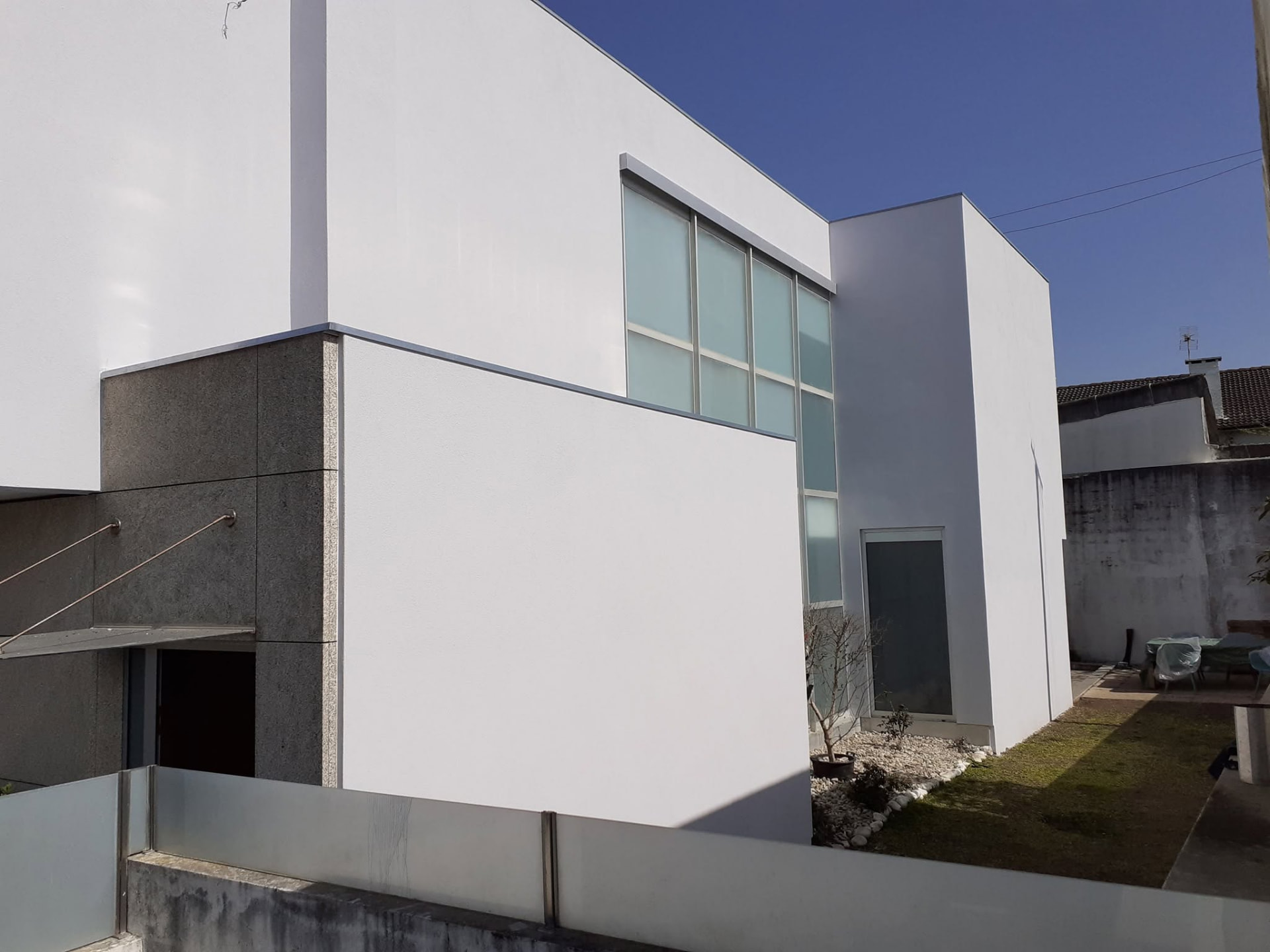 Fachada de moradia reabilitada com sistema ETICS e acabamento branco